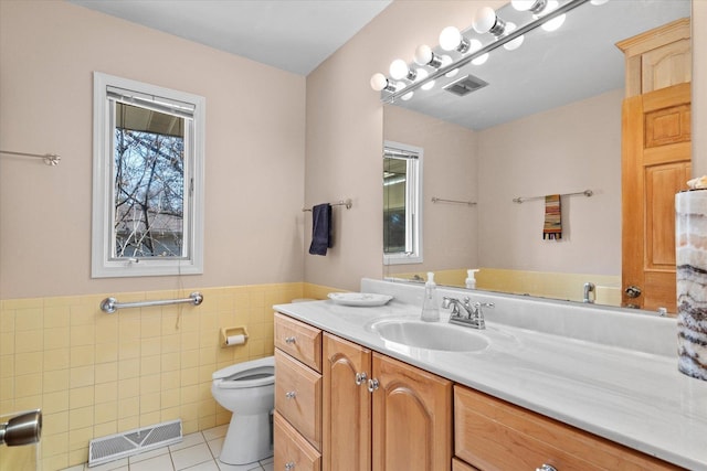 bathroom featuring visible vents, toilet, vanity, tile patterned floors, and tile walls