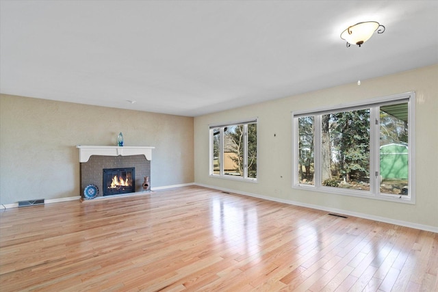 unfurnished living room featuring a fireplace, wood finished floors, visible vents, and baseboards