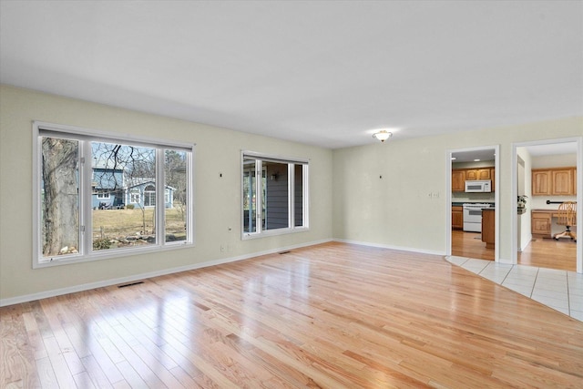 unfurnished living room with visible vents, baseboards, and light wood-style flooring