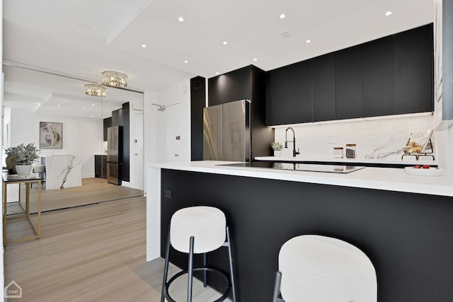 kitchen with light countertops, light wood finished floors, a kitchen bar, and dark cabinets