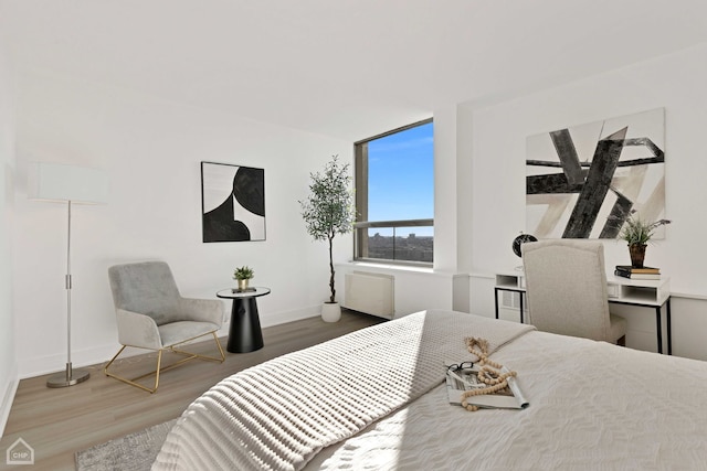 bedroom with radiator heating unit, baseboards, and wood finished floors