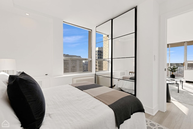 bedroom with visible vents, multiple windows, a city view, and wood finished floors