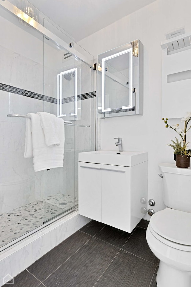 full bath with toilet, a shower stall, vanity, and tile patterned floors