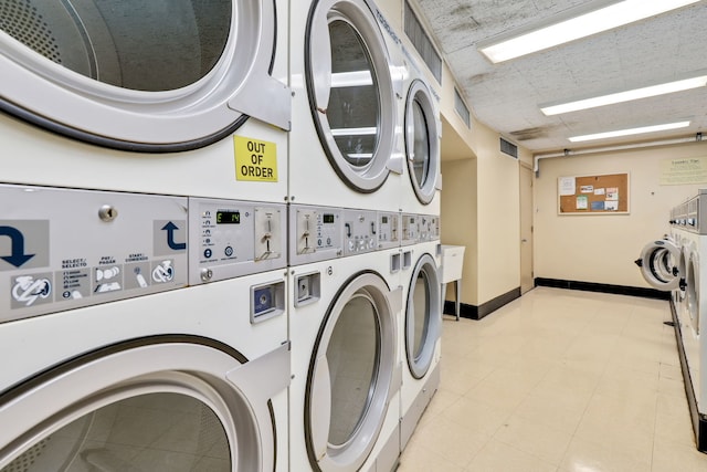 community laundry room with separate washer and dryer, stacked washing maching and dryer, and baseboards