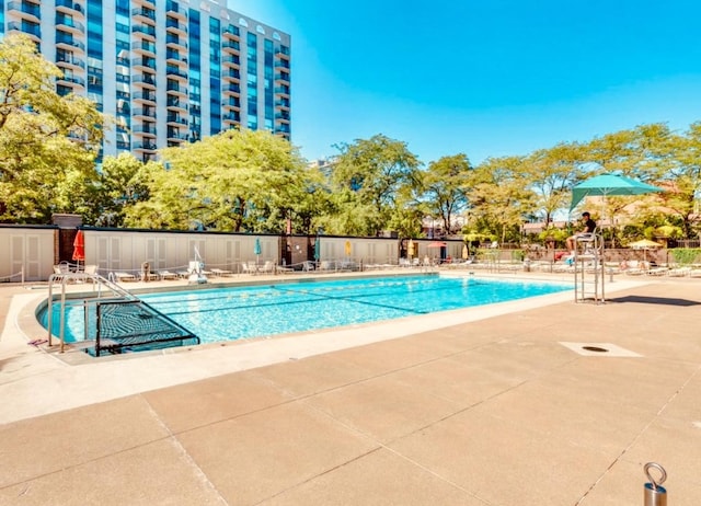 pool with a patio area and fence