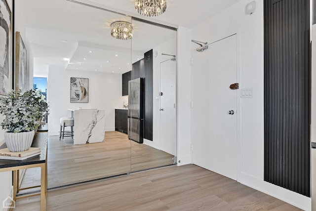 hall featuring light wood finished floors and a notable chandelier