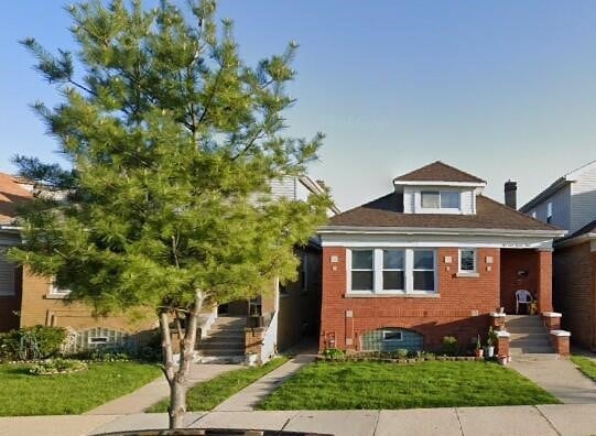 bungalow-style house with a front yard, brick siding, and stairway