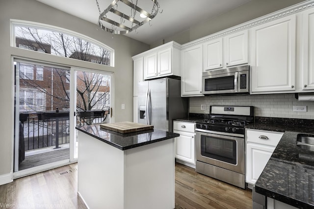 kitchen with stainless steel appliances, tasteful backsplash, white cabinetry, and wood finished floors