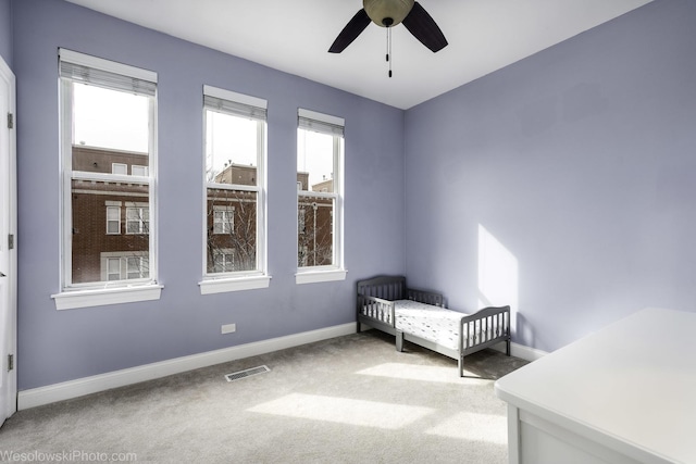 unfurnished bedroom with carpet floors, baseboards, visible vents, and a crib