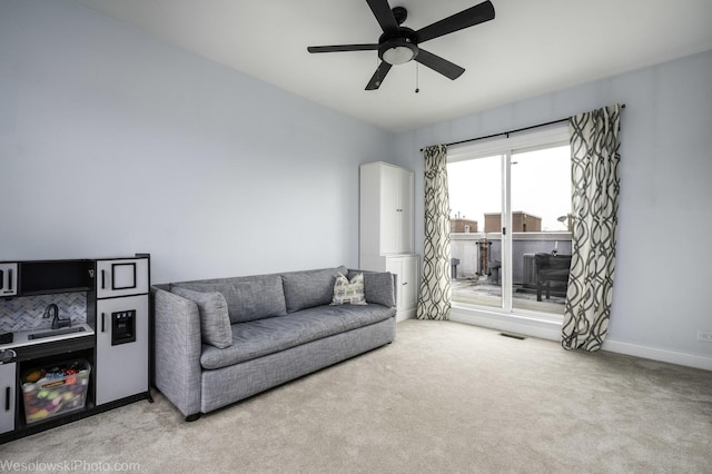 living area with visible vents, baseboards, a ceiling fan, and light colored carpet