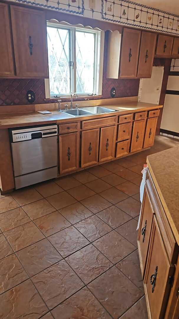 kitchen with a sink, backsplash, refrigerator, light countertops, and dishwasher