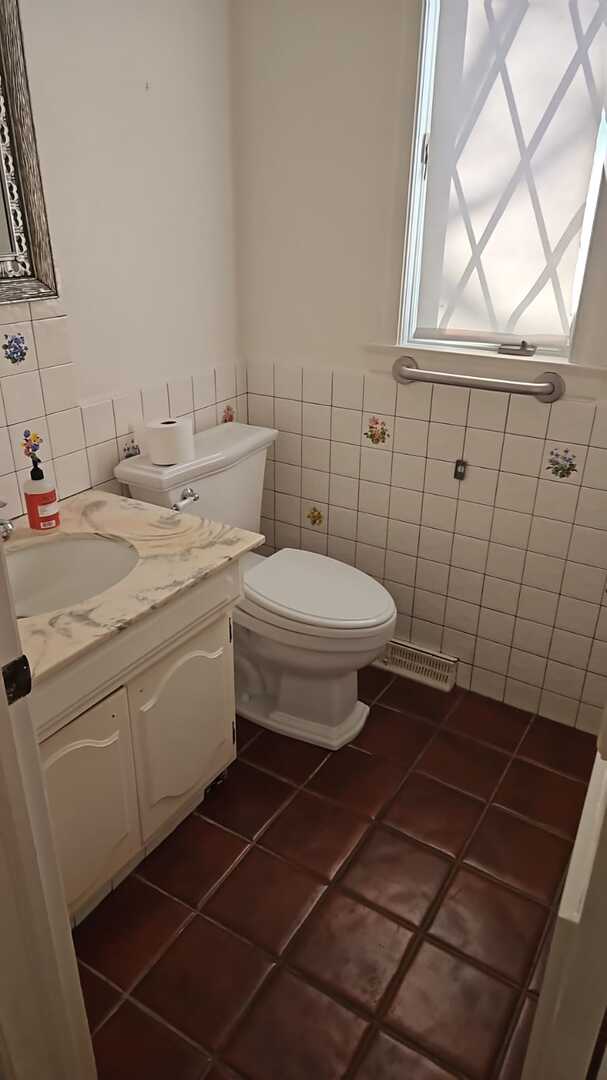 bathroom featuring vanity, visible vents, tile patterned floors, toilet, and tile walls