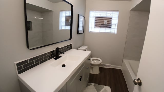 bathroom featuring a healthy amount of sunlight, vanity, toilet, and wood finished floors