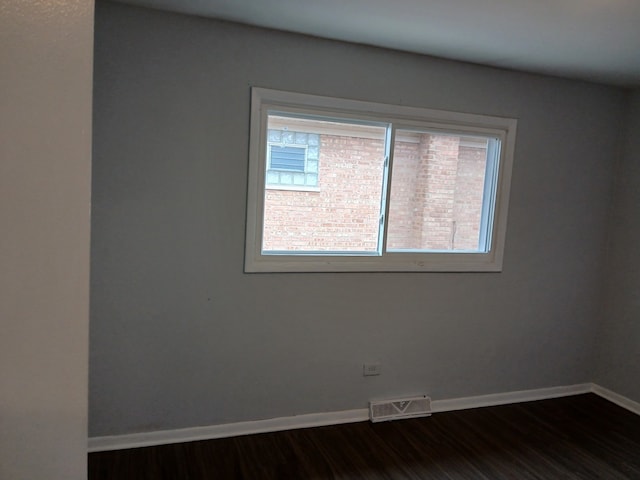 empty room featuring dark wood finished floors, visible vents, and baseboards