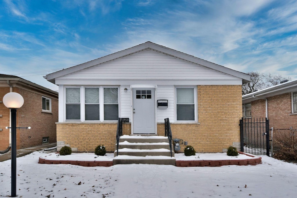 bungalow featuring brick siding and fence