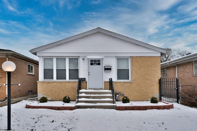 bungalow featuring brick siding and fence