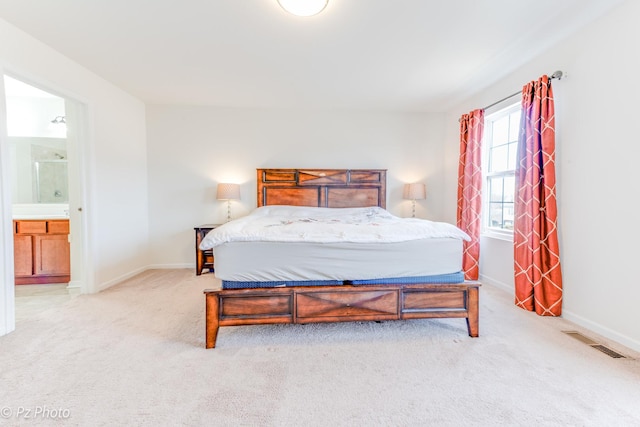 bedroom with light carpet, visible vents, connected bathroom, and baseboards