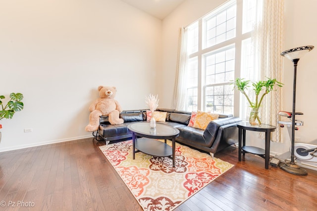 living room featuring hardwood / wood-style flooring, a high ceiling, and baseboards