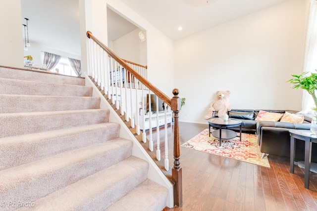 staircase featuring recessed lighting, baseboards, a towering ceiling, and hardwood / wood-style flooring