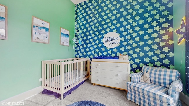 bedroom with baseboards, a nursery area, and carpet flooring