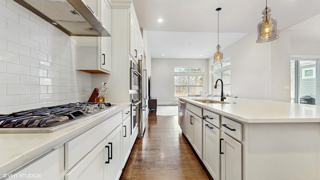 kitchen featuring dark wood-type flooring, under cabinet range hood, appliances with stainless steel finishes, white cabinetry, and a sink