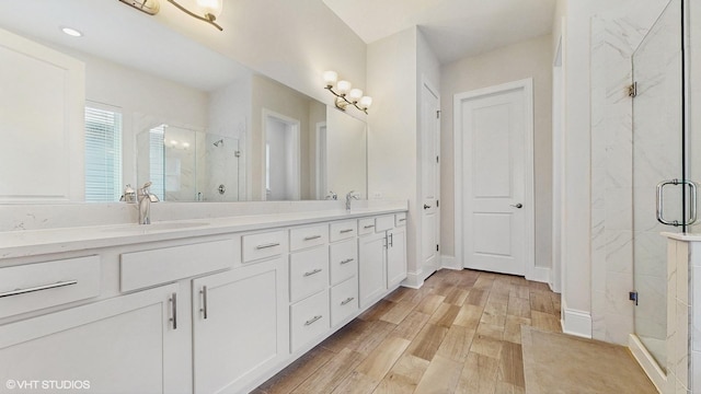 full bath featuring double vanity, wood finished floors, a stall shower, and a sink