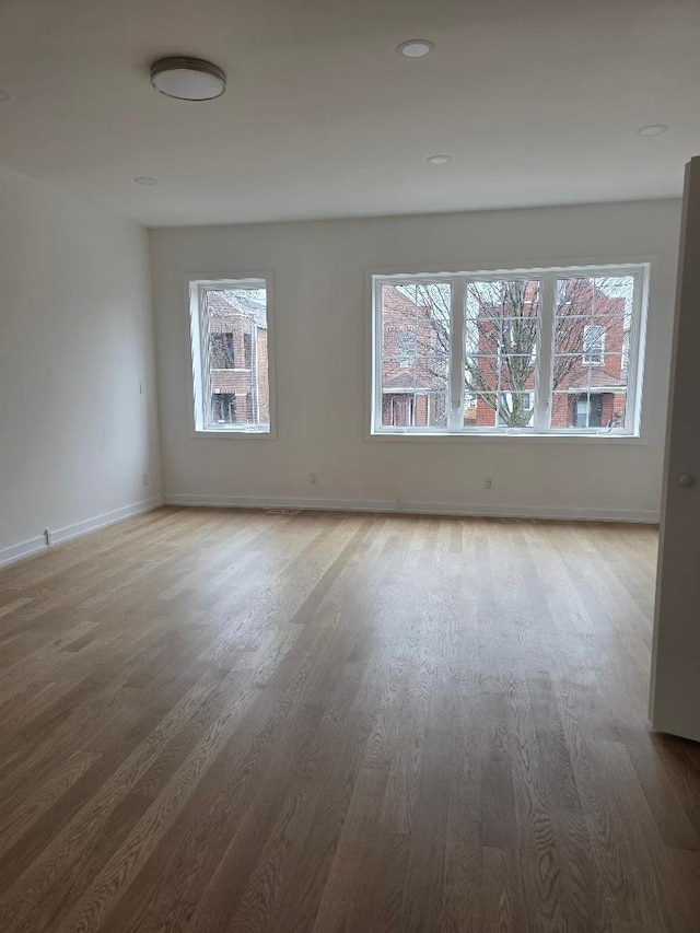 empty room featuring baseboards, a wealth of natural light, and wood finished floors