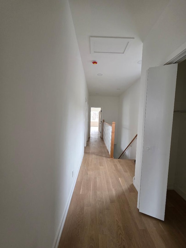 corridor with attic access, baseboards, an upstairs landing, and wood finished floors