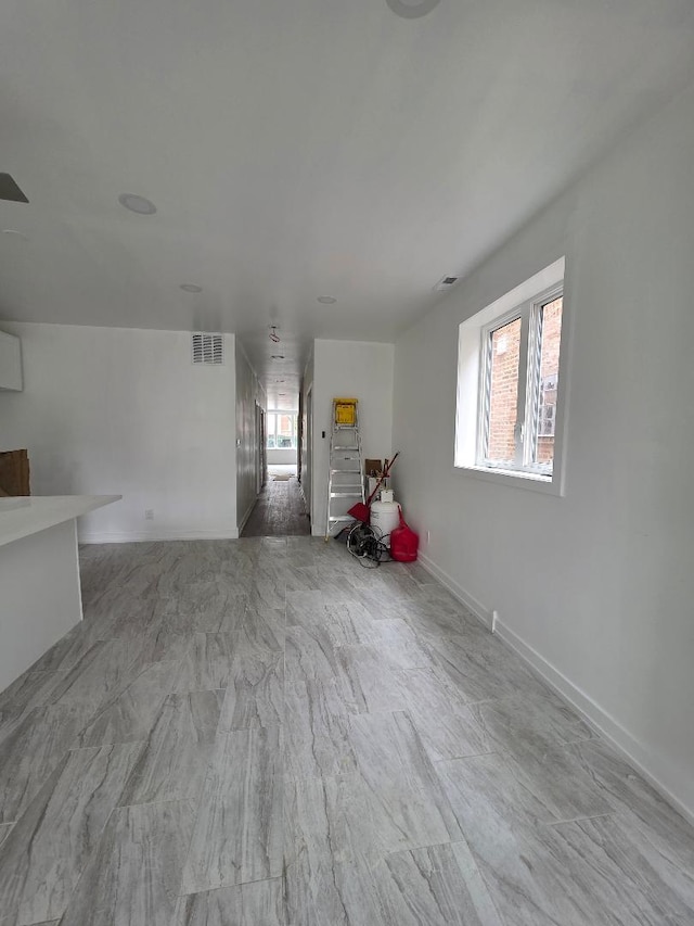 unfurnished living room with visible vents and baseboards