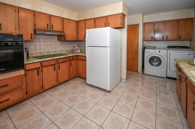 kitchen with under cabinet range hood, washer and clothes dryer, light countertops, brown cabinetry, and black appliances