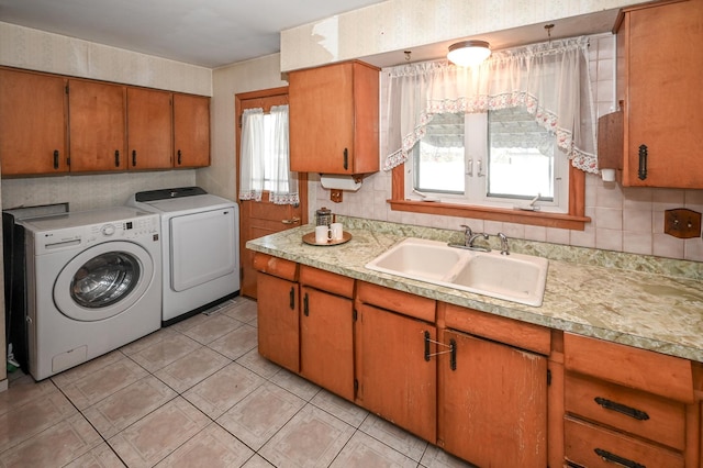 clothes washing area with a sink, light tile patterned floors, cabinet space, and washer and clothes dryer