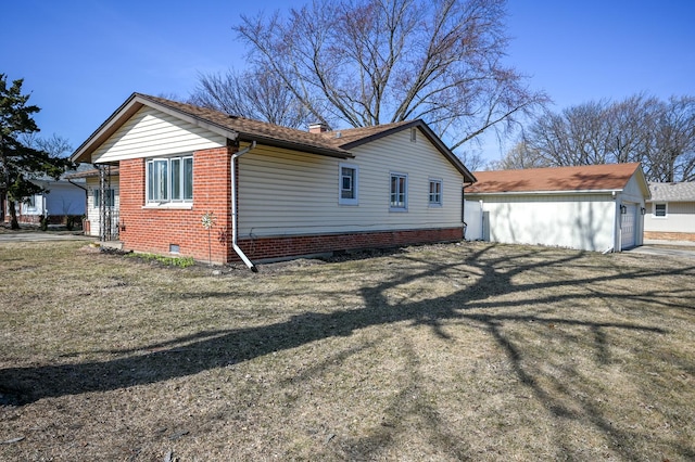 view of side of property with brick siding, a lawn, a chimney, a garage, and an outdoor structure