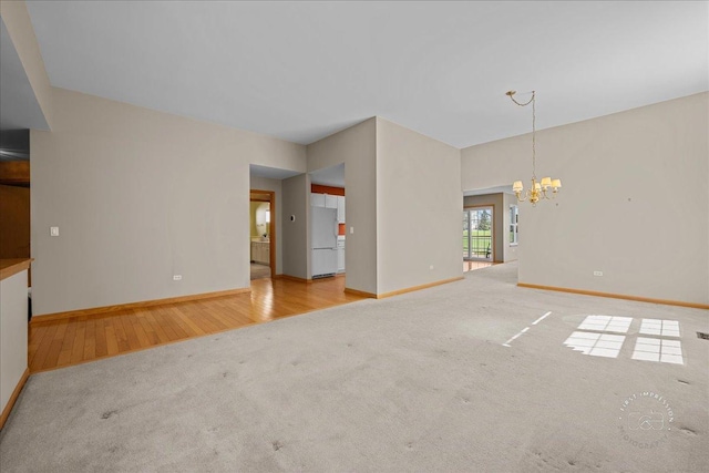 13731 S Tamarack Dr, Plainfield, IL 60544 - unfurnished living room featuring carpet, wood finished floors, a chandelier, and baseboards