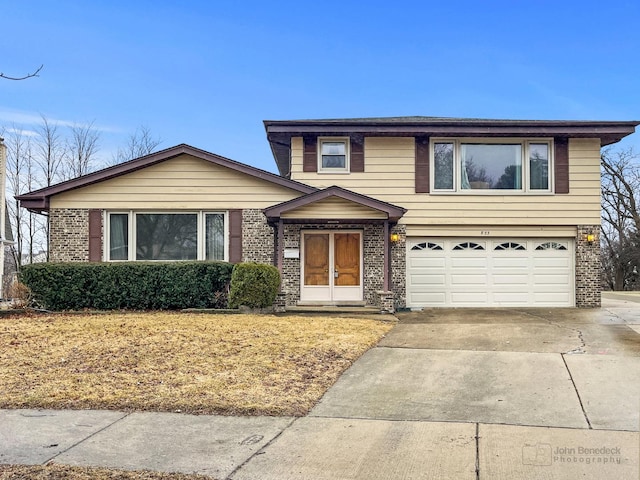 view of front of house featuring a garage, concrete driveway, and brick siding