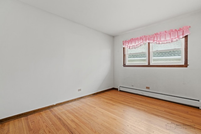 empty room with baseboards, baseboard heating, and wood finished floors