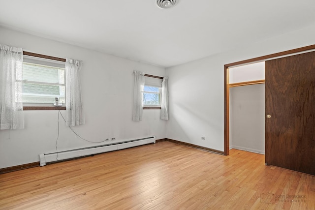 unfurnished bedroom featuring a baseboard heating unit, visible vents, light wood-style floors, and baseboards