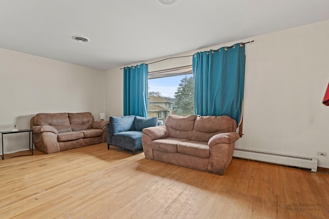 living area featuring a baseboard heating unit, hardwood / wood-style floors, and visible vents