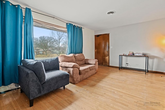 living area with baseboards, visible vents, and wood finished floors