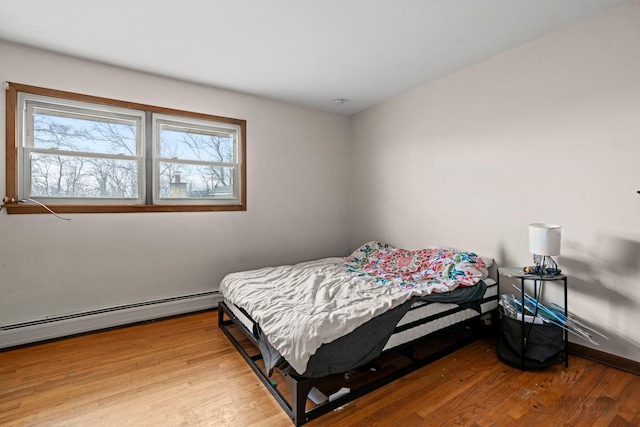 bedroom with baseboard heating and wood finished floors