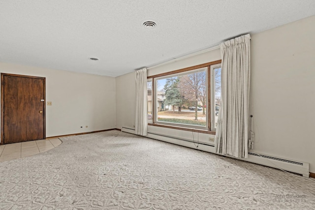 empty room with a baseboard radiator, visible vents, a textured ceiling, and baseboards