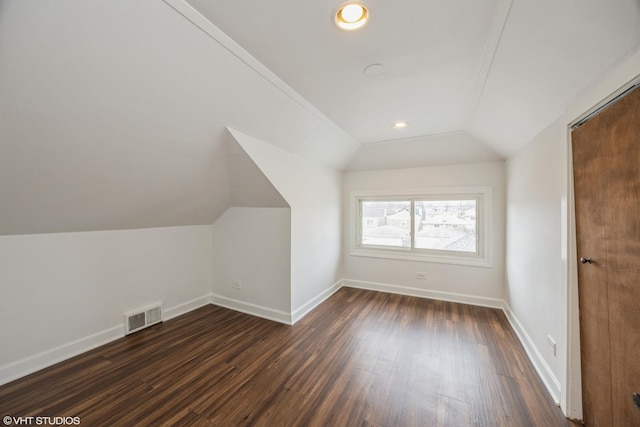 additional living space with lofted ceiling, baseboards, visible vents, and dark wood-type flooring