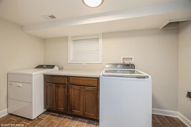 washroom featuring cabinet space, baseboards, visible vents, wood finish floors, and separate washer and dryer