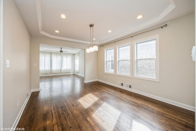 interior space featuring dark wood-type flooring, visible vents, baseboards, ornamental molding, and a tray ceiling