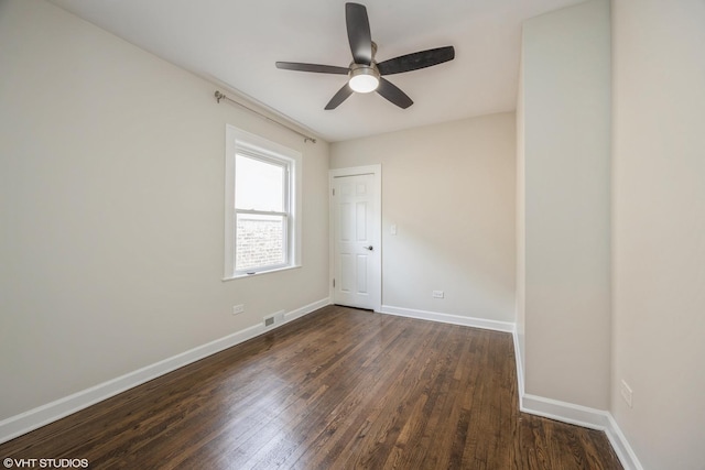 spare room with dark wood-style floors, visible vents, ceiling fan, and baseboards