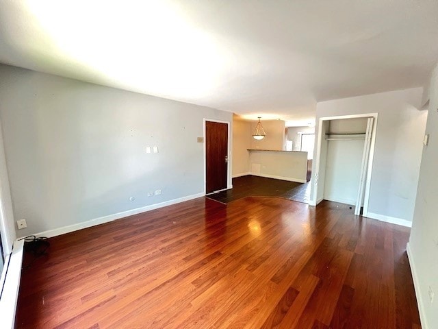 unfurnished living room featuring wood finished floors and baseboards