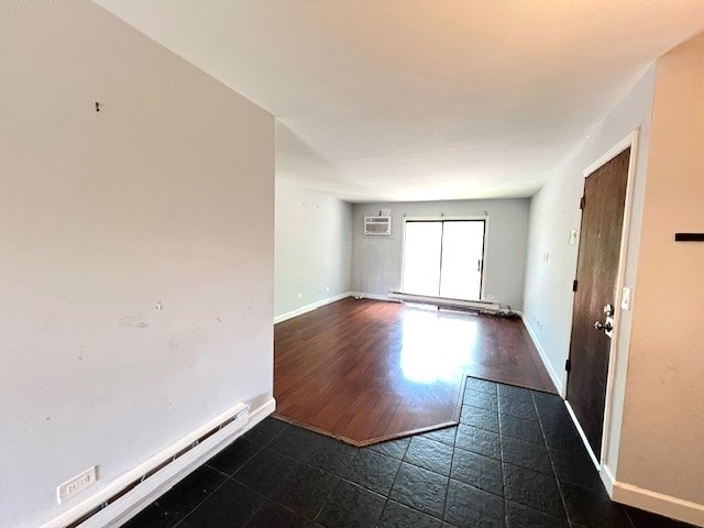 empty room with a baseboard radiator, a wall unit AC, and baseboards