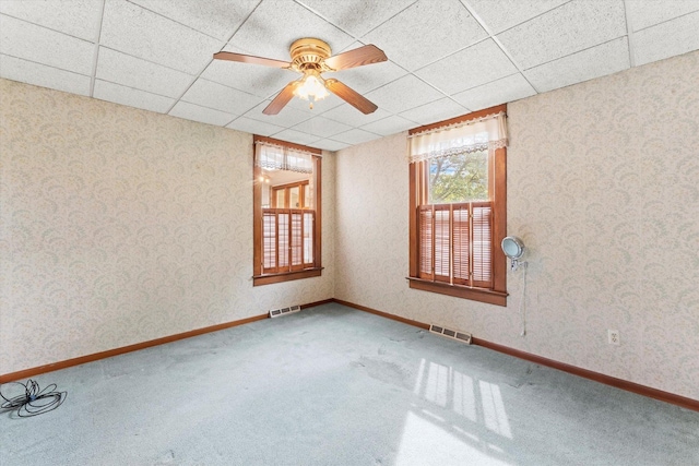 unfurnished room with a paneled ceiling, wallpapered walls, carpet, and visible vents