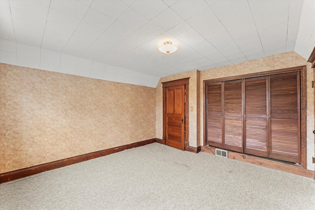 unfurnished bedroom with visible vents, baseboards, a closet, carpet, and wallpapered walls