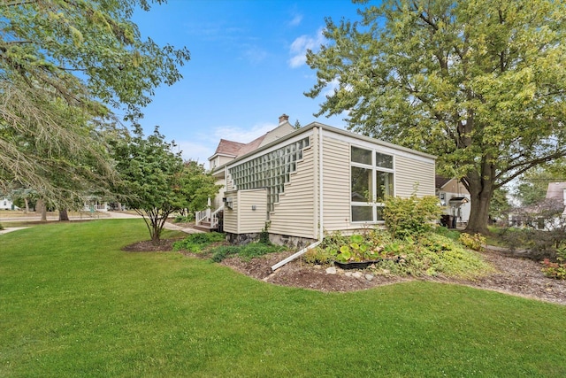 view of home's exterior featuring a chimney and a yard