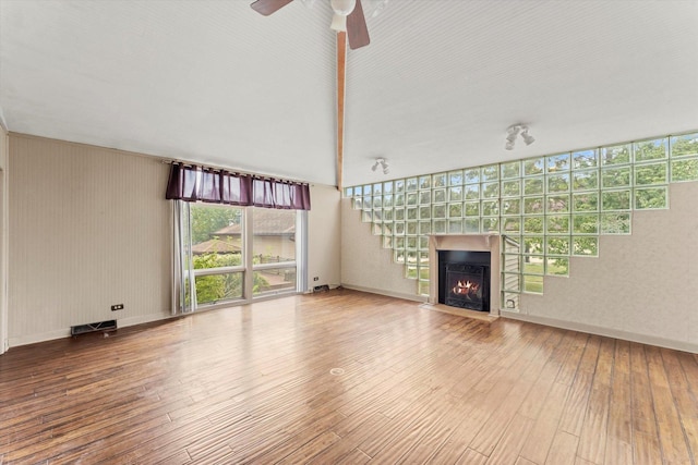 unfurnished living room featuring wood-type flooring, a fireplace with flush hearth, and baseboards